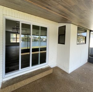 Covered back patio with sliding glass doors and white brick walls