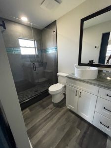 Remodeled Bathroom with Grey Woodgrain Tile, and High End black shower tiles