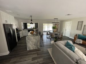 Remodeled living area with kitchen island, dining table, and gray flooring
