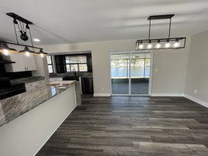 Remodeled dining area and kitchen with sliding glass doors and gray flooring