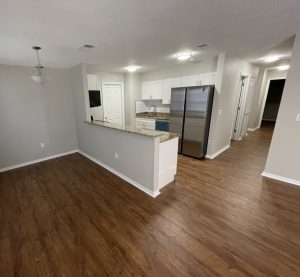 Remodeled kitchen with white cabinets and woodgrain flooring