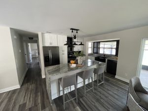 Remodeled kitchen with large island, bar seating, and gray flooring