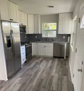 Remodeled kitchen with white shaker cabinets, gray tile backsplash, and stainless appliances