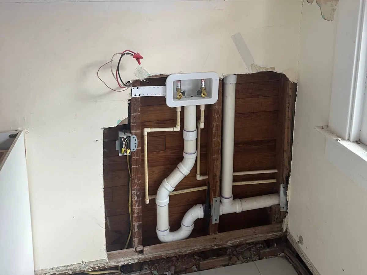 Tactical Construction Group plumbing repair in progress: a new washer outlet box, drain and supply lines in an opened wall